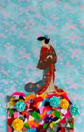 This contemporary collage juxtaposes a traditional Japanese ukiyo-e style figure against a serene, cherry-blossom-patterned background. The composition is anchored by a vibrant, tactile pile of multicolored felt scraps and artificial flowers, blending historical aesthetics with playful modern materials. The work explores cross-cultural themes through the layering of paper, fabric, and craft elements.