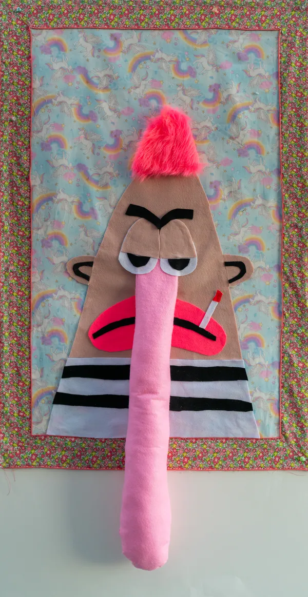 This tactile textile collage features a weary character with a plush, elongated nose and neon pink hair set against a whimsical background of rainbows and unicorns. The piece masterfully blends kitsch aesthetics with a sense of modern disillusionment through its use of soft fabrics and irreverent imagery. Sayre explores cross-cultural pop sensibilities using unconventional materials to create a bold, wall-mounted presence.