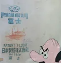 This piece utilizes a vintage Japanese flour sack as a substrate, featuring weathered industrial typography and a faded steamship illustration. A bold, hand-painted pink cartoon character is juxtaposed against the found object, exploring the intersection of Western pop aesthetics and Japanese commercial history. The stained, aged texture of the textile adds a sense of history and cross-cultural dialogue to the playful composition.